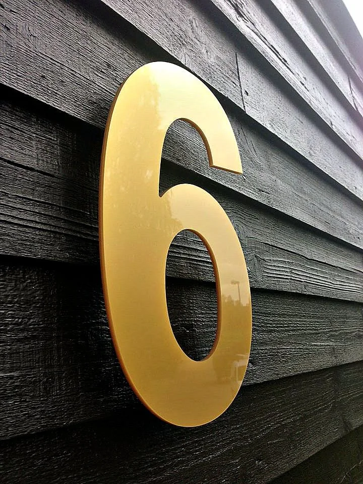 Husnummer 6 i gul akryl på svart fasad