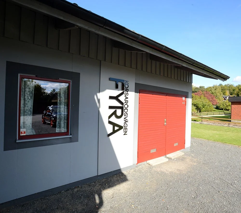 Ordet "Korsarodsvägen FYRA" husbokstäverna i svart akryl på vit cementvägg