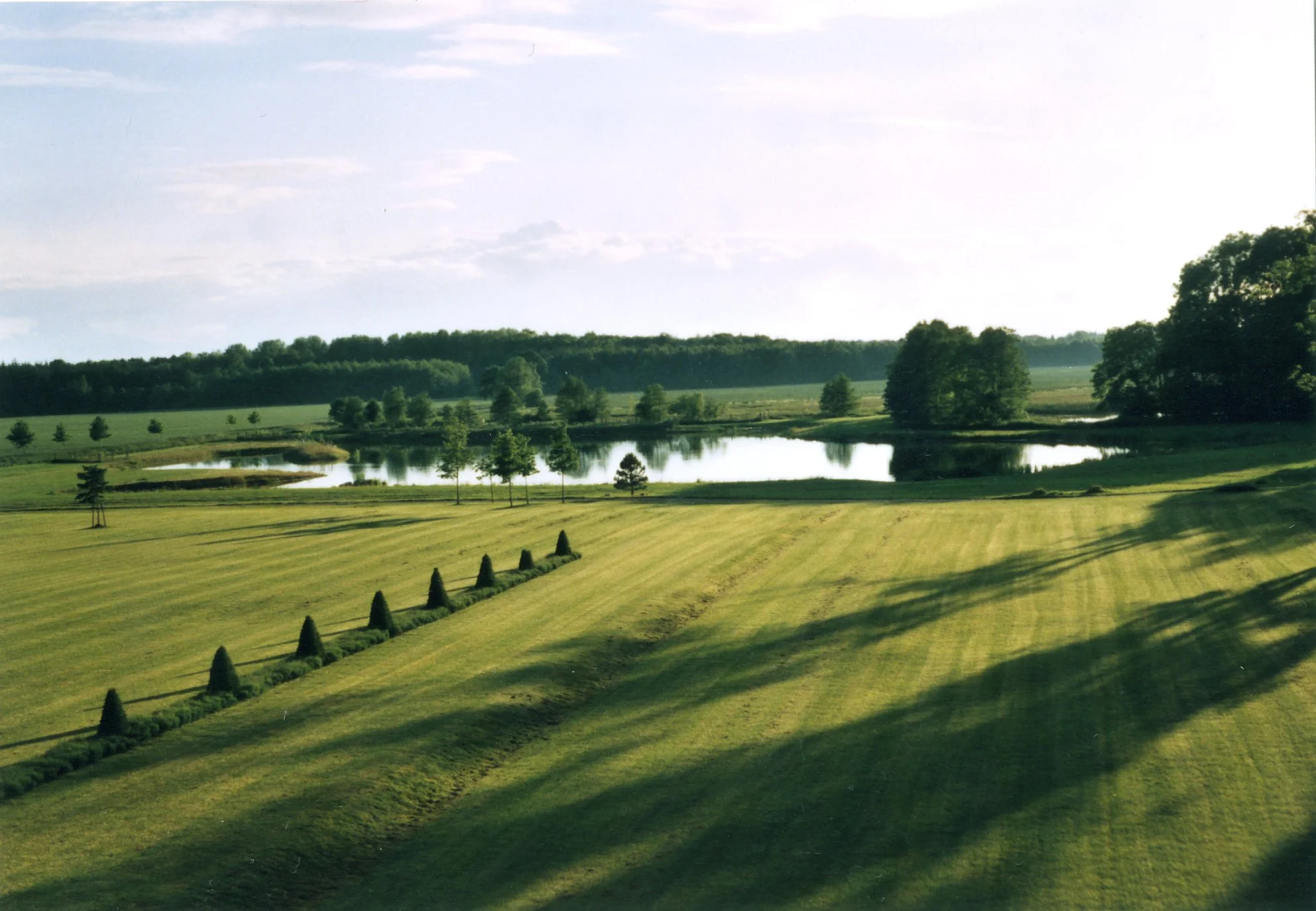 Landschaft mit einem See, Bäumen und einem weiten, gepflegten Rasen in Deutschland.