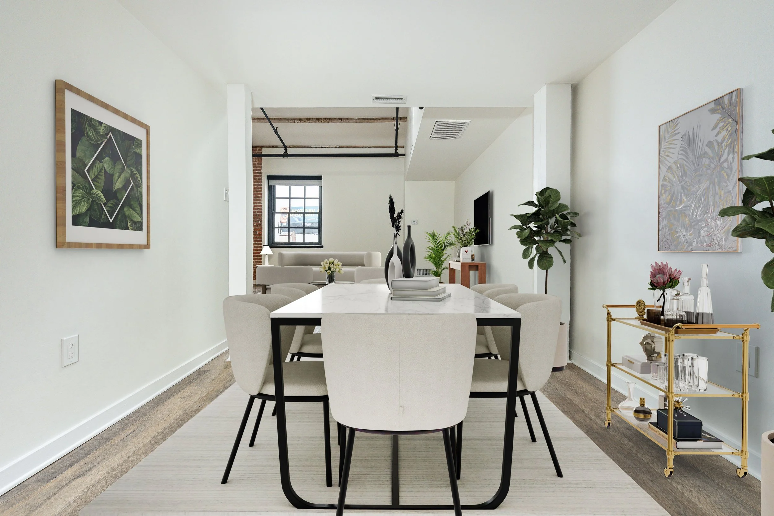Modern living and dining room with white walls, wooden floors, framed artwork, green plants, marble dining table with white chairs, and a gold bar cart with glassware.