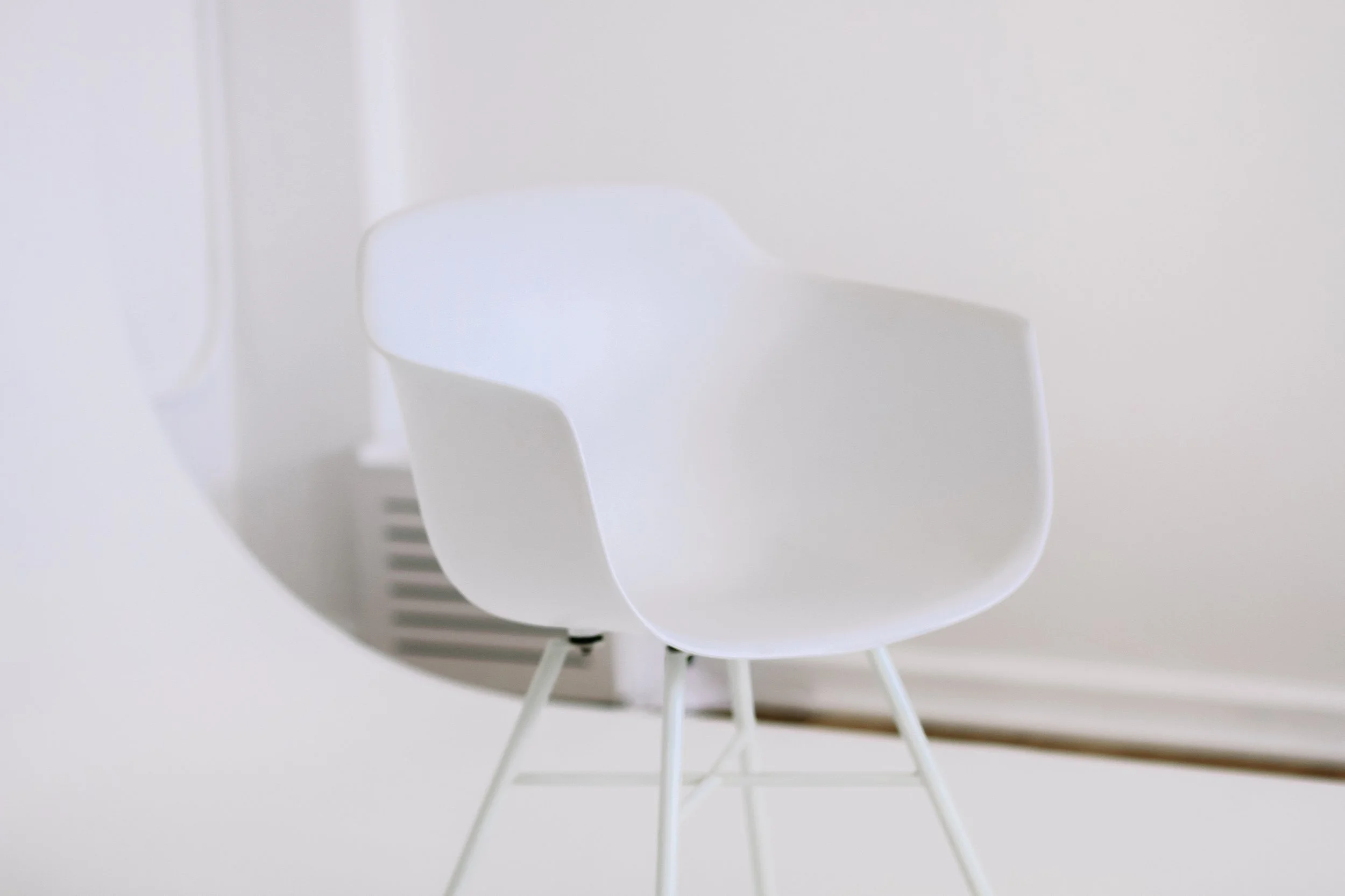 Close-up of a white modern chair against a plain white background.