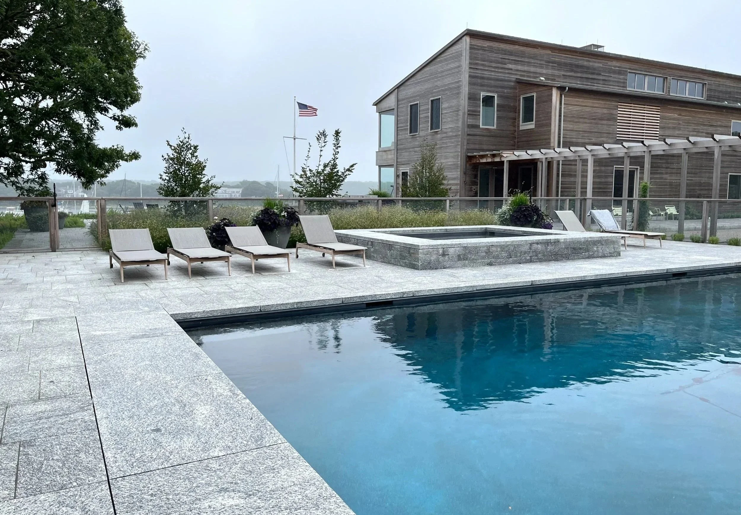 Swimming pool and spa with granite paving at family compound, coastal Massachusetts.