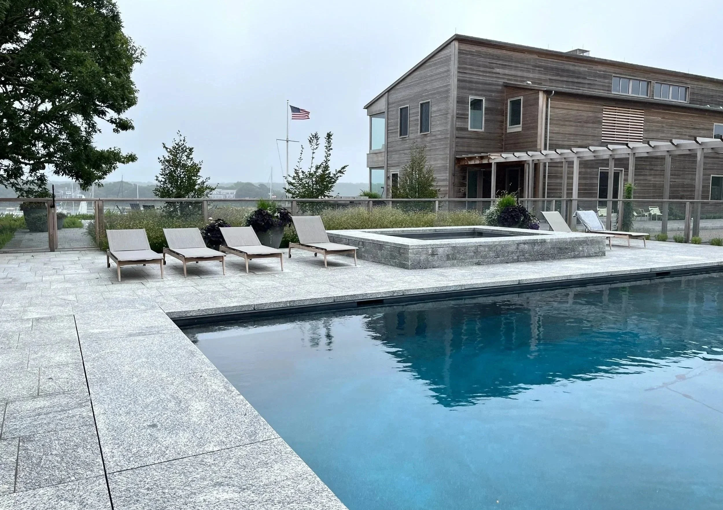Swimming pool and spa with granite paving at family compound, coastal Massachusetts.