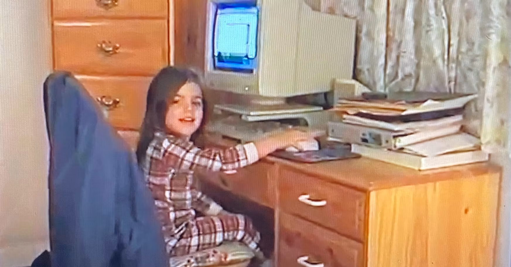 child in plaid pajamas sitting at a desktop computer