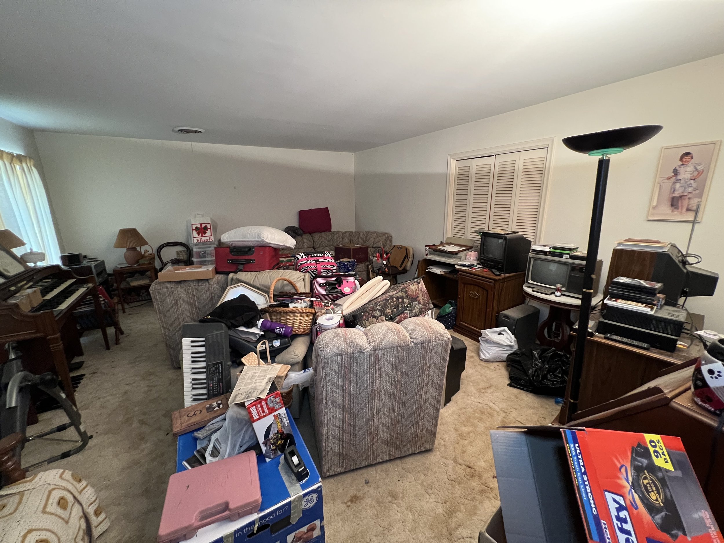 Living room cluttered with furniture, boxes, and various household items.