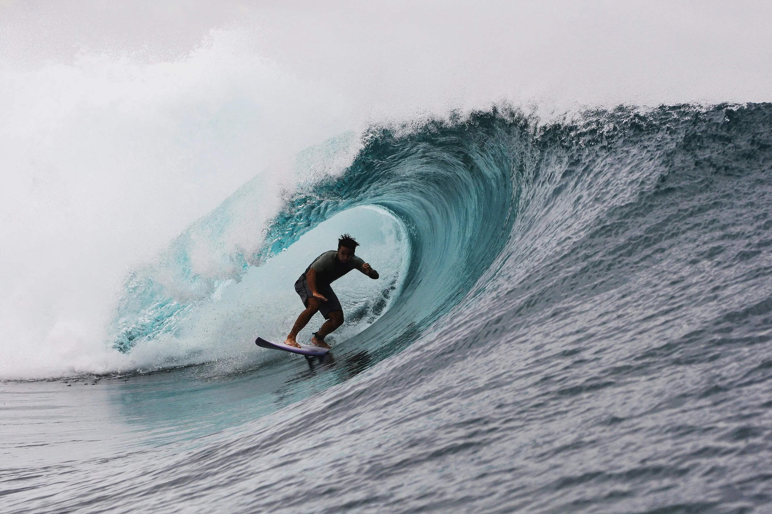 A man surfing inside the barrel of a large ocean wave.