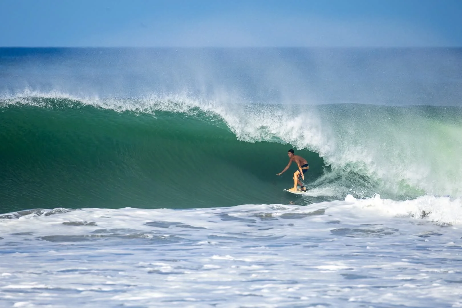 A person surfing on a green wave at the beach during daytime.