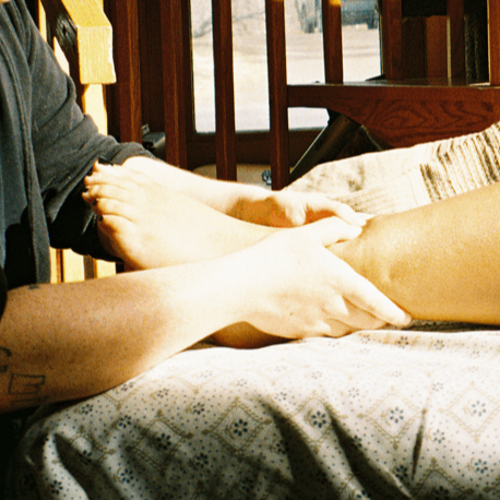 A person receiving a massage on their arm from another person at a wooden table.