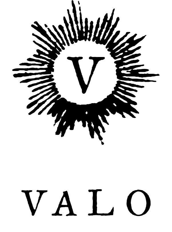 A black background with a white burst shape surrounding a large letter 'V' in the center. Below, the word 'VALO' is written in white capital letters, with the letter 'O' featuring a speckled or textured design.