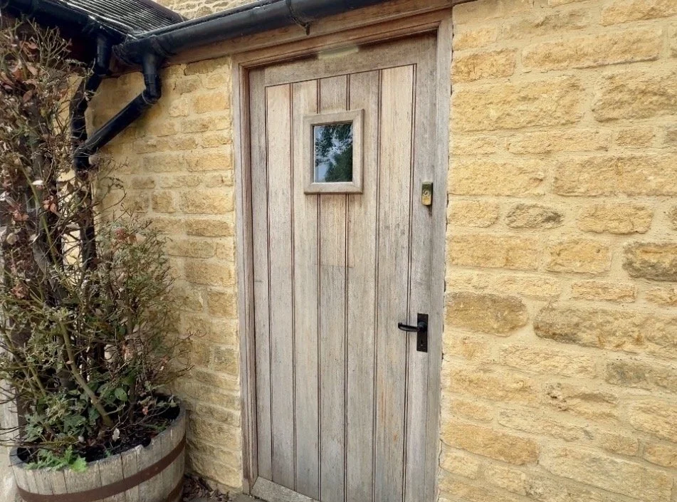 Wooden door with a small window in a brick wall exterior.