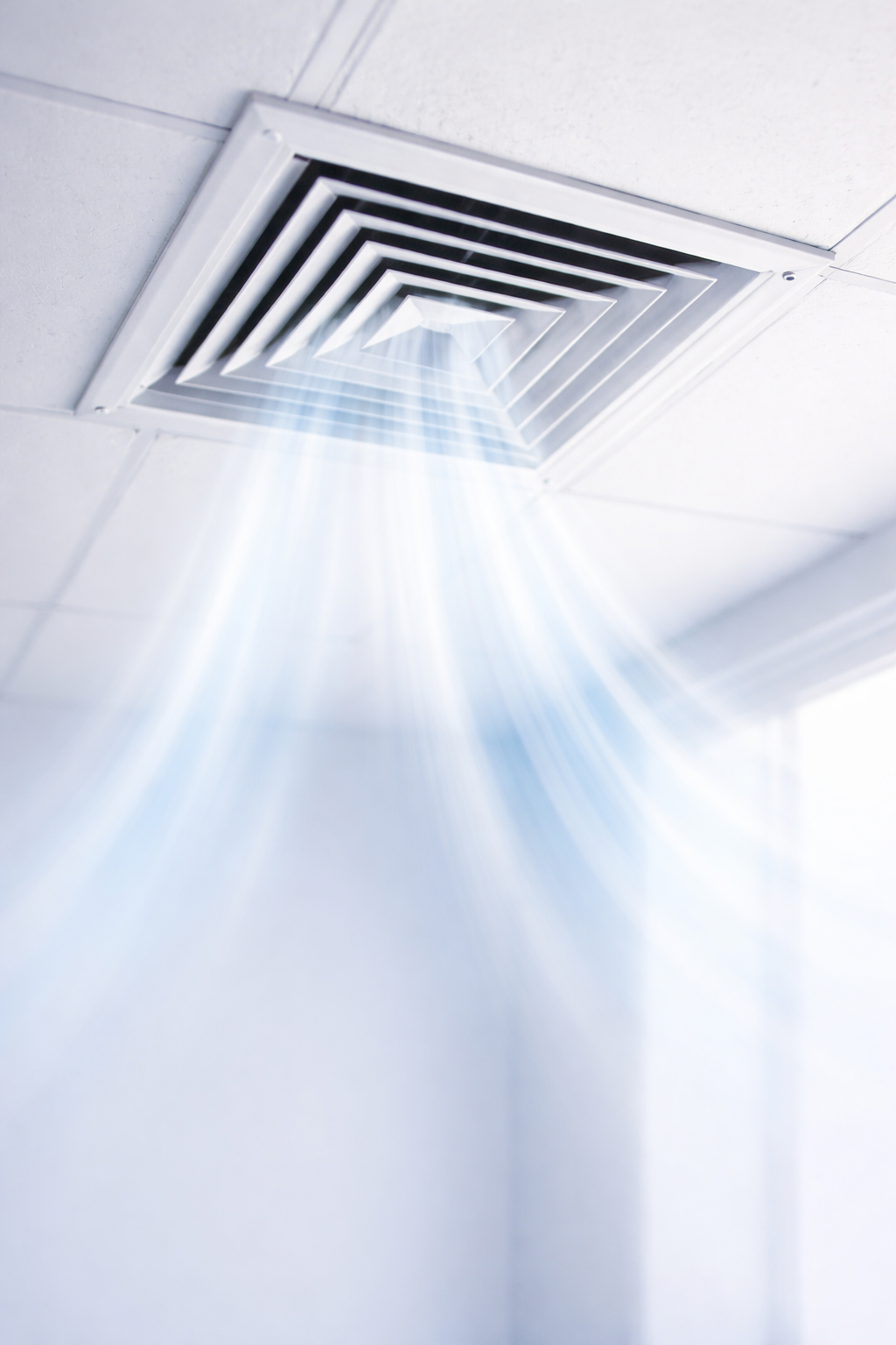 Une bouche d'aération dans un plafond, laissant passer la lumière à travers des rayons bleus.