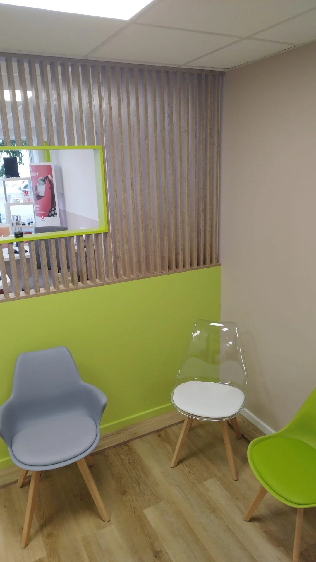 Trois chaises modernes dans une salle d'attente ou un espace de détente avec un mur en bois clair et une paroi verte