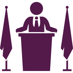 Silhouette of a person standing behind a podium with two flags, one on each side.