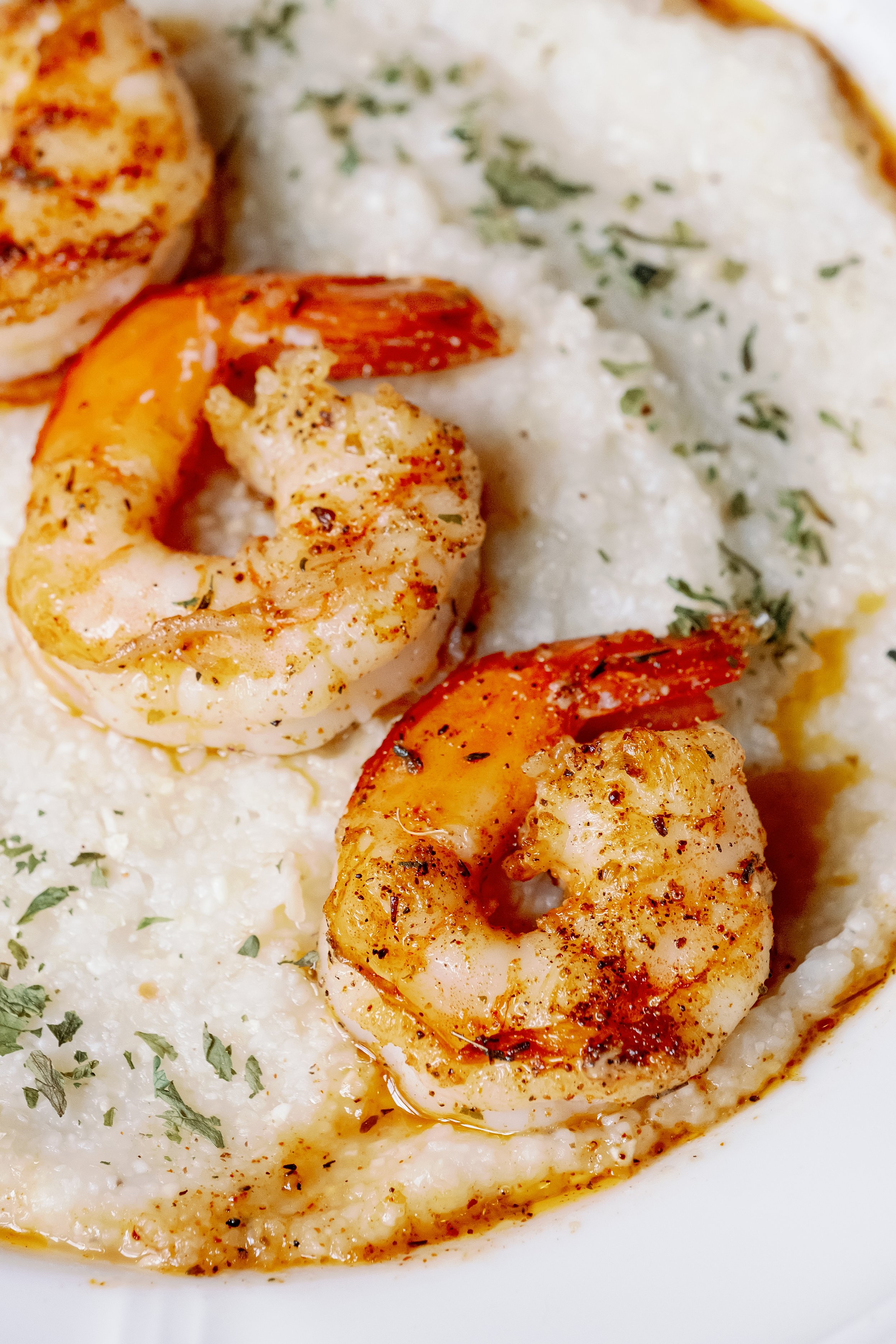 Shrimp served over creamy grits garnished with herbs.