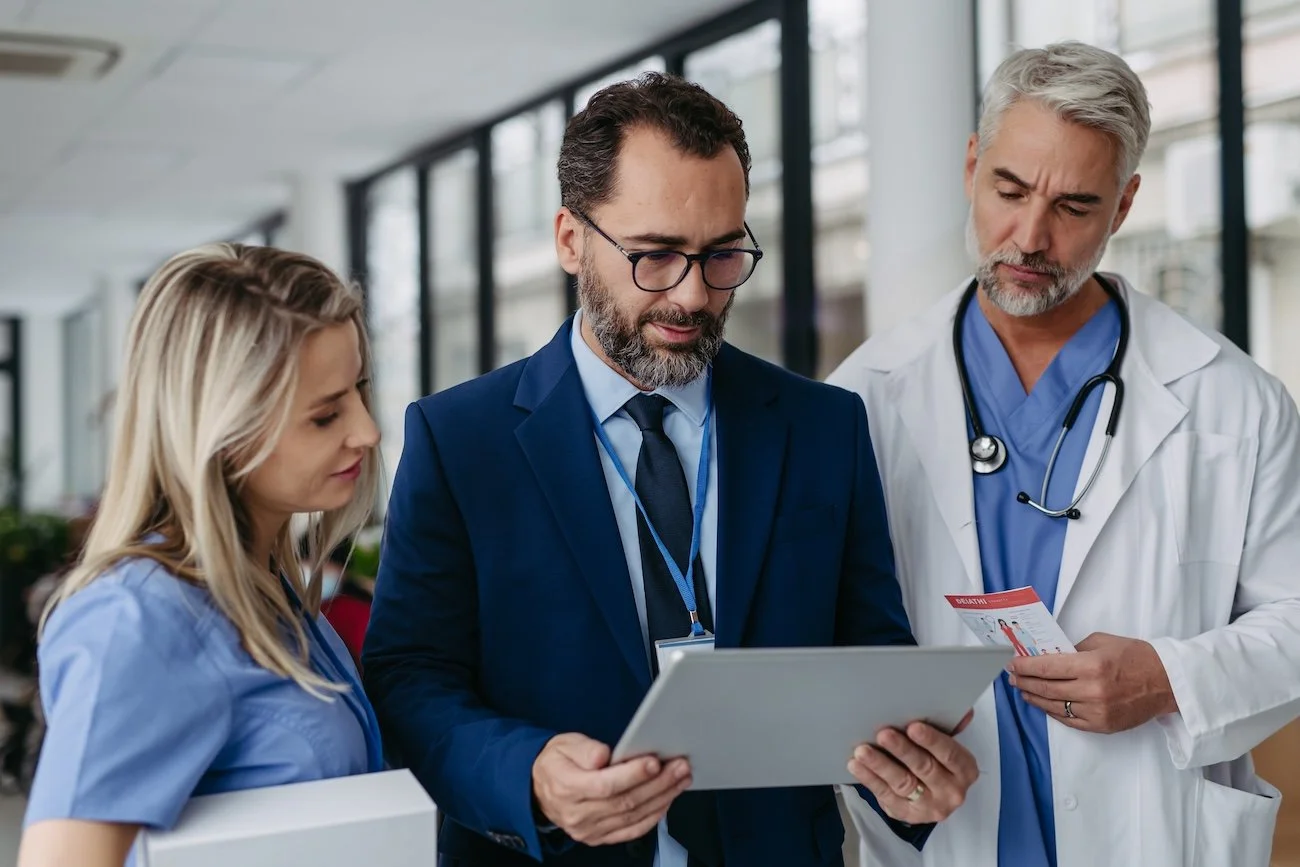 Two healthcare providers and one healthcare IT consultant, reviewing ServiceNow platform information on a tablet in a hospital.