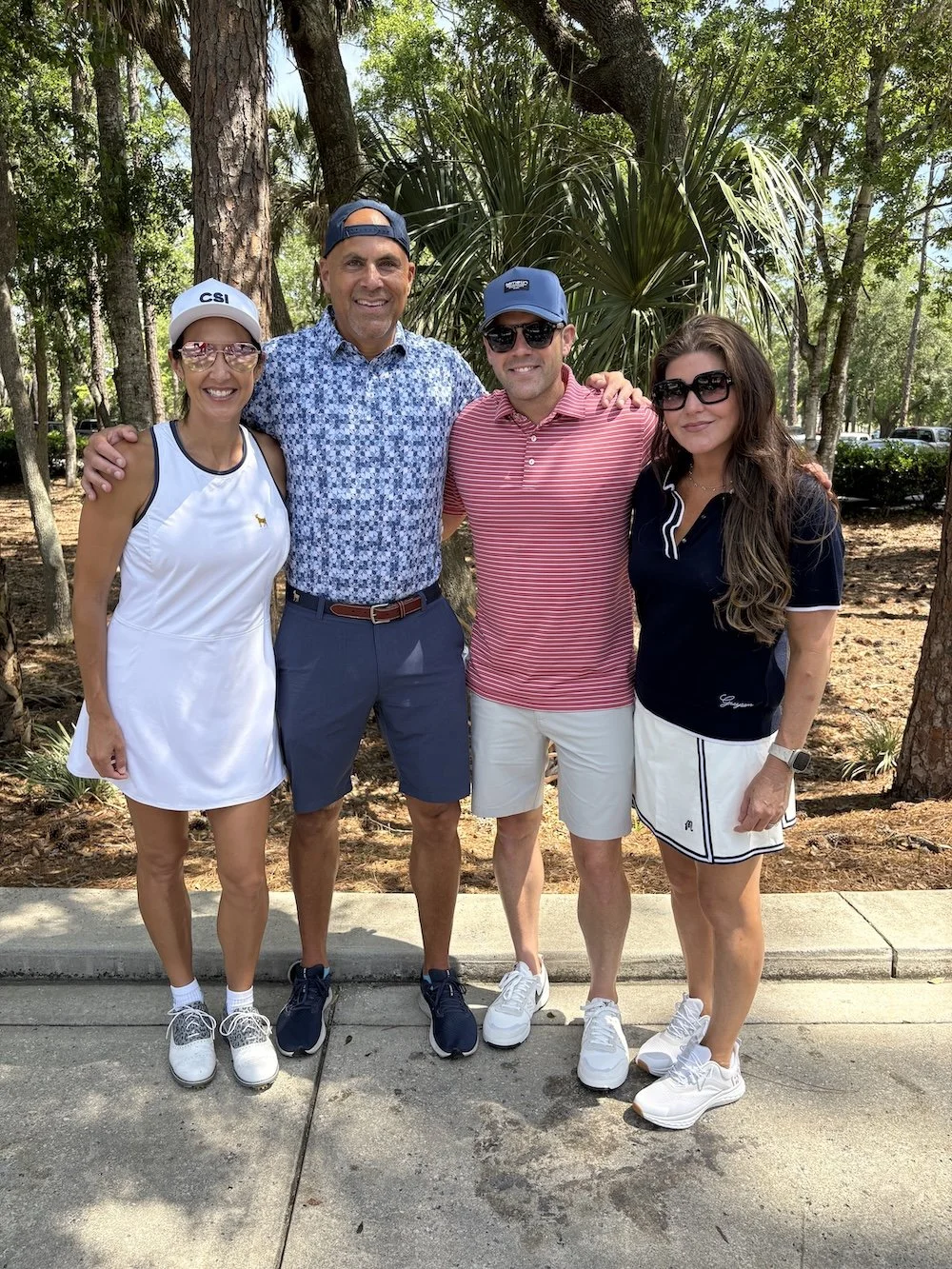 Four CSI leadership team members standing outdoors on a sunny day in a park, smiling.