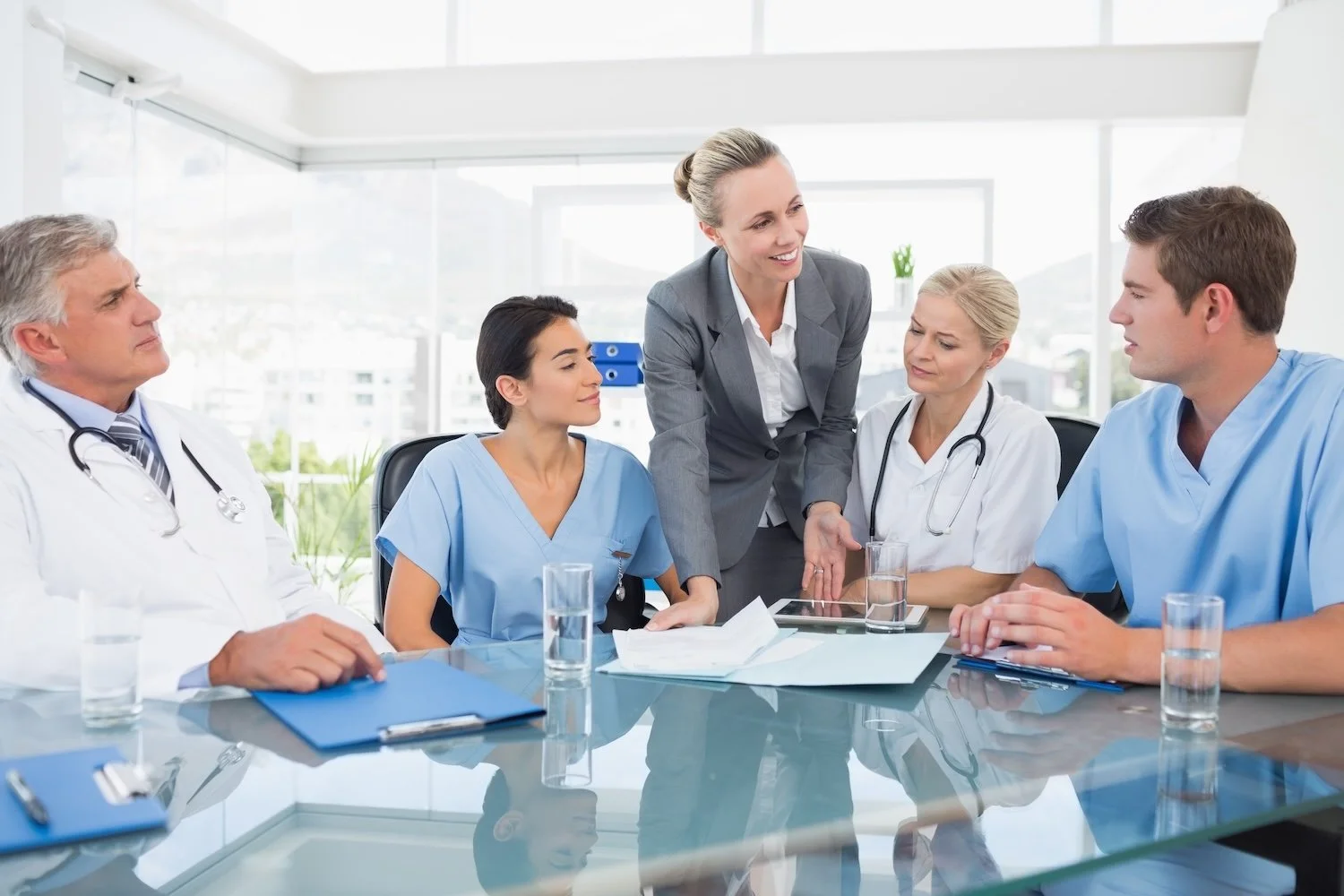 A group of medical professionals, including doctors and nurses, in a meeting room discussing epic refuel support with a healthcare IT leader.