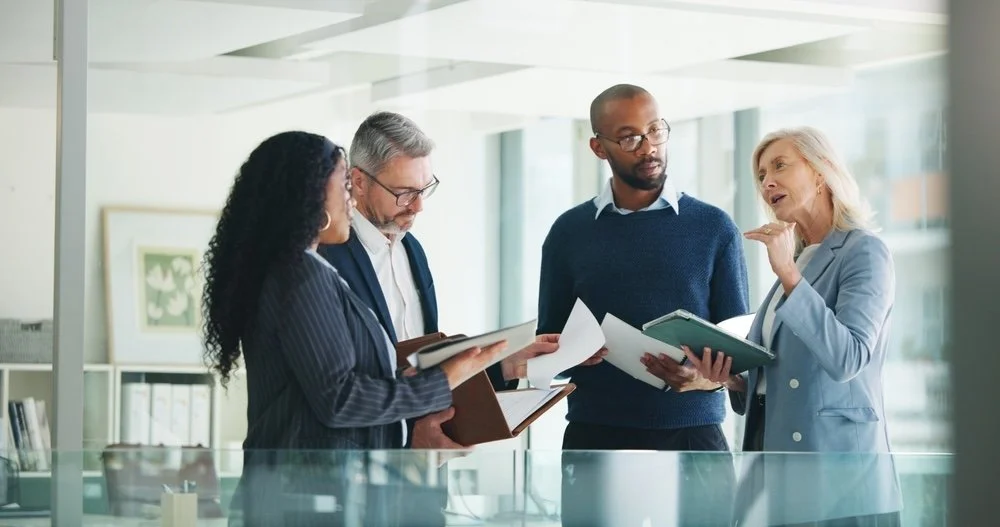 Four diverse healthcare IT consultants having a discussion in a modern office conference room about technical services.