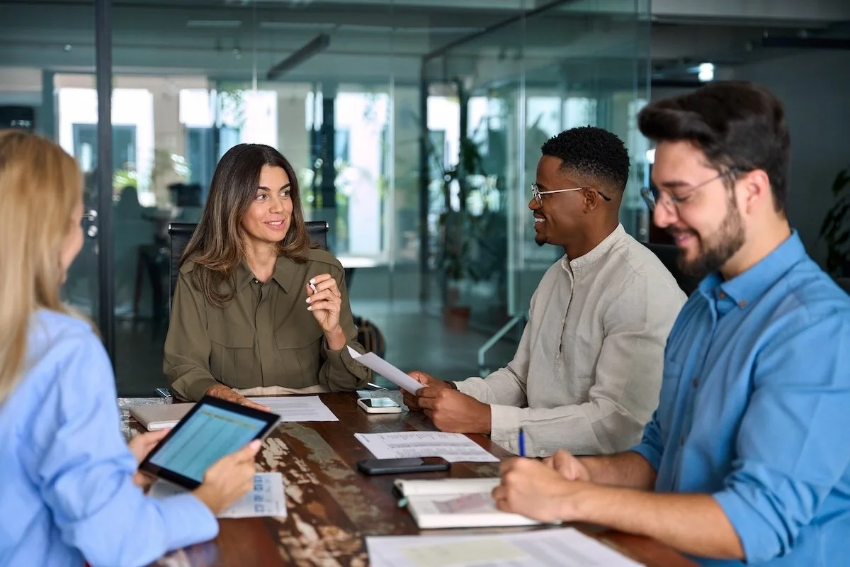 Four diverse healthcare IT professionals having a discussion about Epic implementation around a conference table in a modern office.