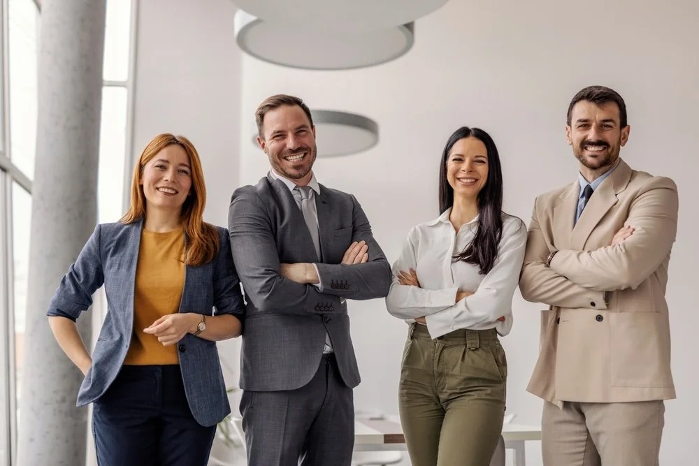 Group of healthcare IT consultants posing for a photo inside a bright office building.