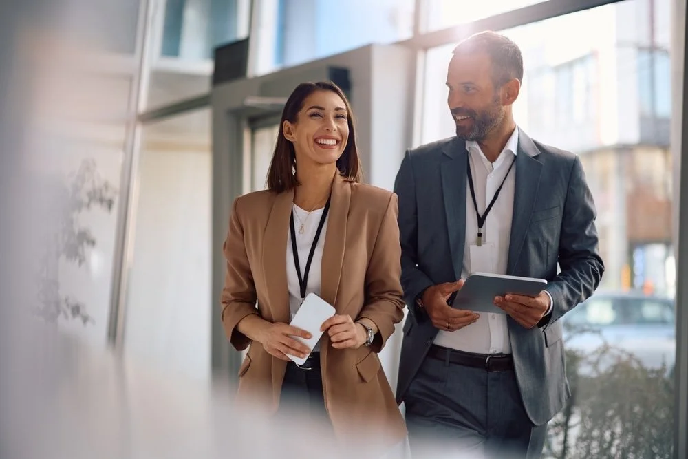 two healthcare IT consultants walking together with their work badges on into a healthcare organization with high glass windows