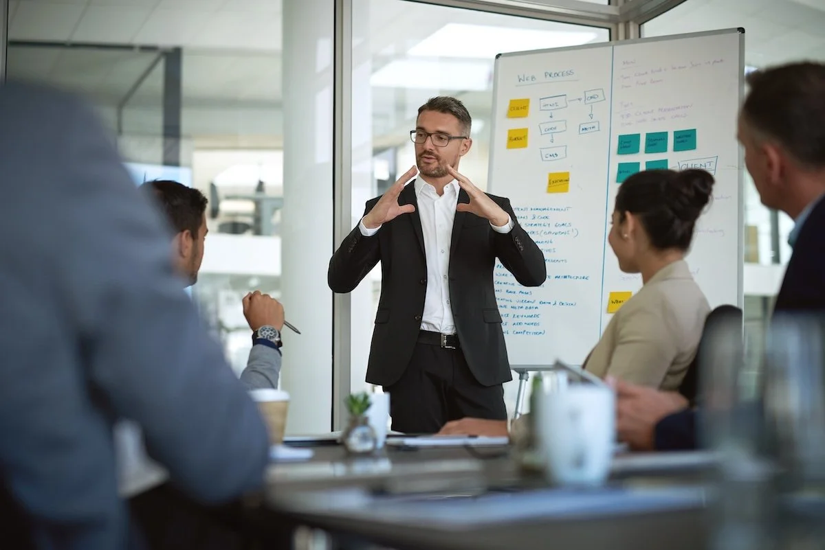 Group of healthcare IT leaders gathered around a meeting table, reviewing hiring solutions on a white board.