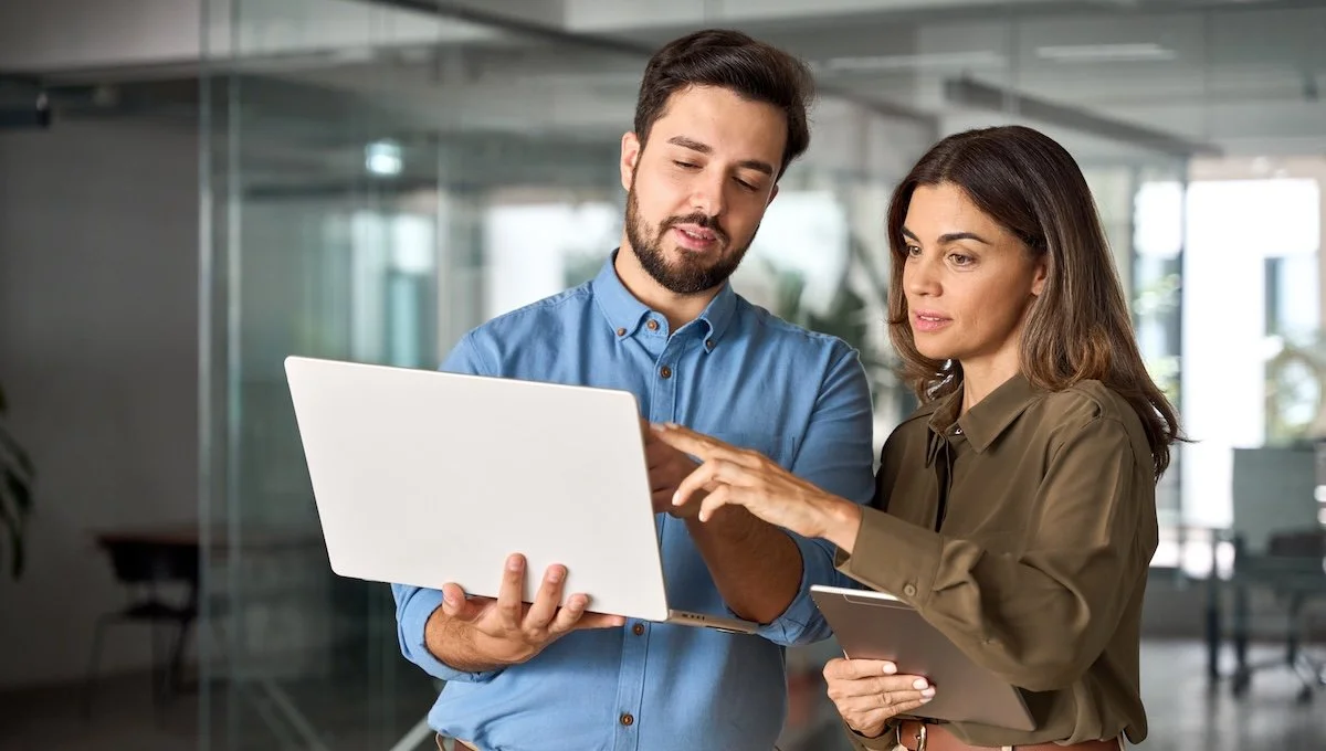 two healthcare IT consultants reviewing data on a laptop together