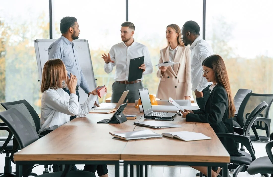 Team of healthcare it consultant in a meeting room with tall glass windows, discussing clinical documentation integrity programs.
