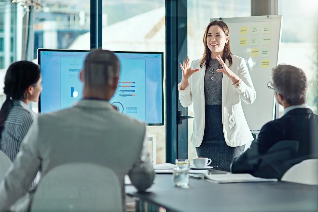 Healthcare IT consultant presenting in a modern office, coding and CDI education to healthcare leaders on a screen.