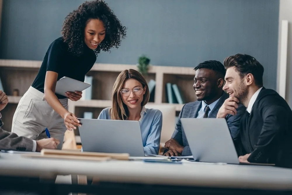 Four consultants working together in an office looking at a laptop screen.