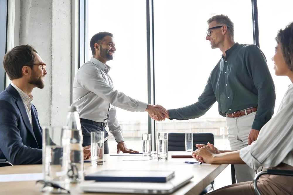 Healthcare IT leaders meeting in a modern office shaking hands before leadership meeting starts.