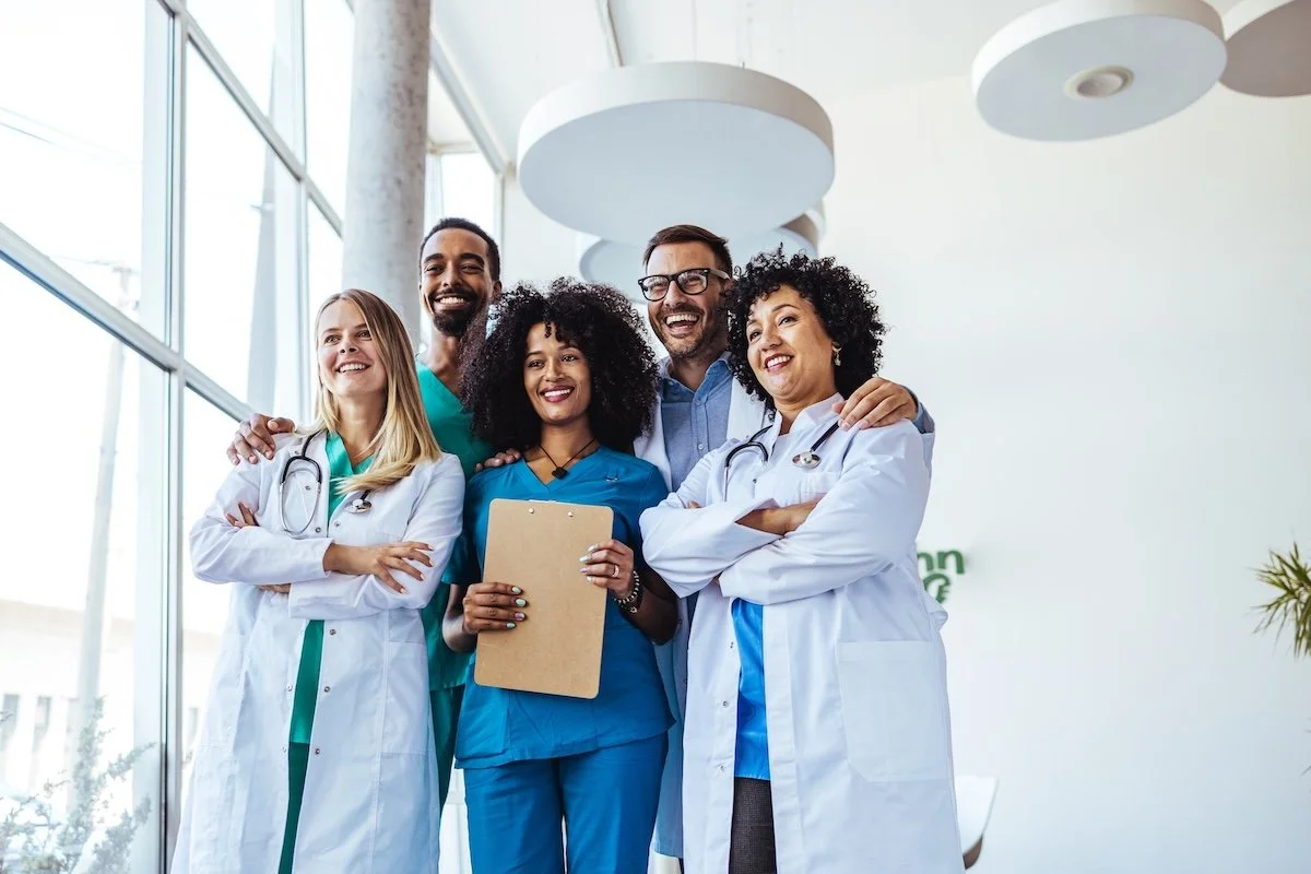 Group of healthcare providers standing happily posing for a photo inside hospital. 