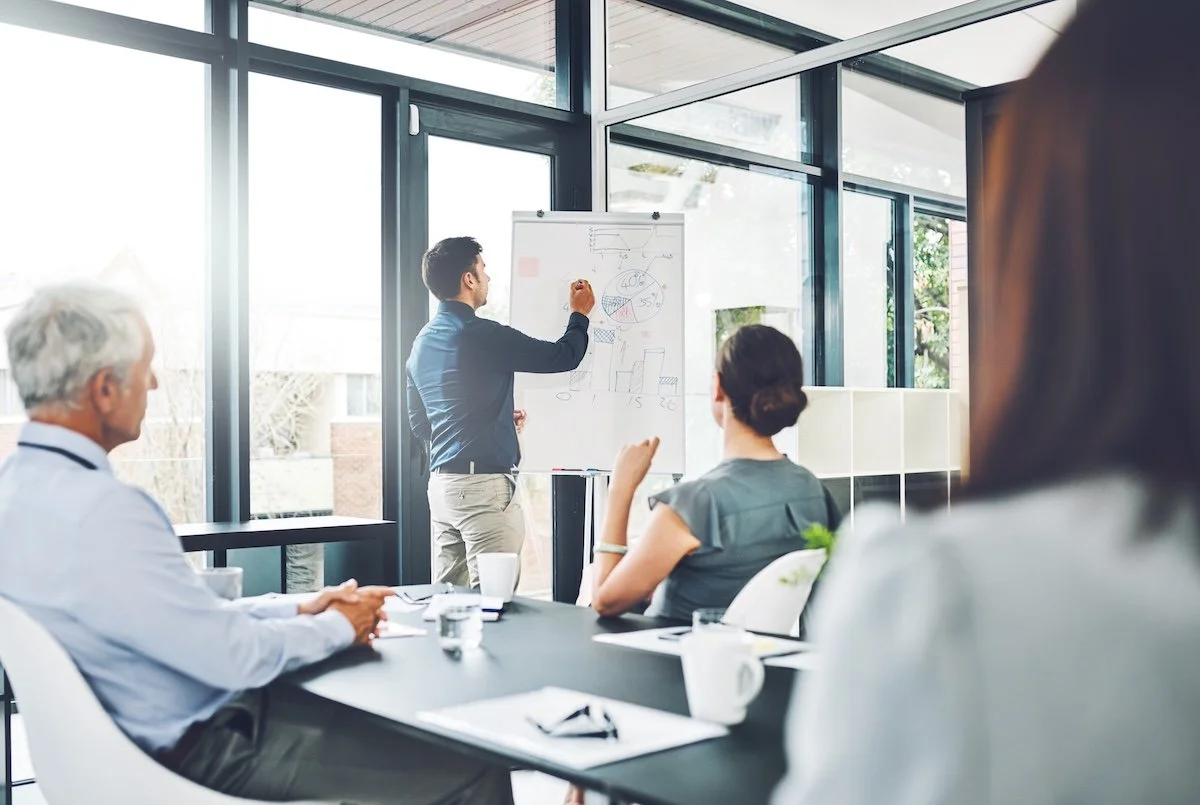 Healthcare IT professionals meeting and reviewing revenue cycle management data on whiteboards.  