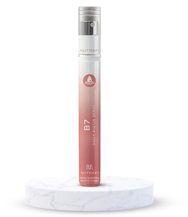 A tall, cylindrical spray bottle with a transparent cap and white pump, labeled NutraFi B7 Daily Biotin Spray, standing on a round marble platform against a white background.