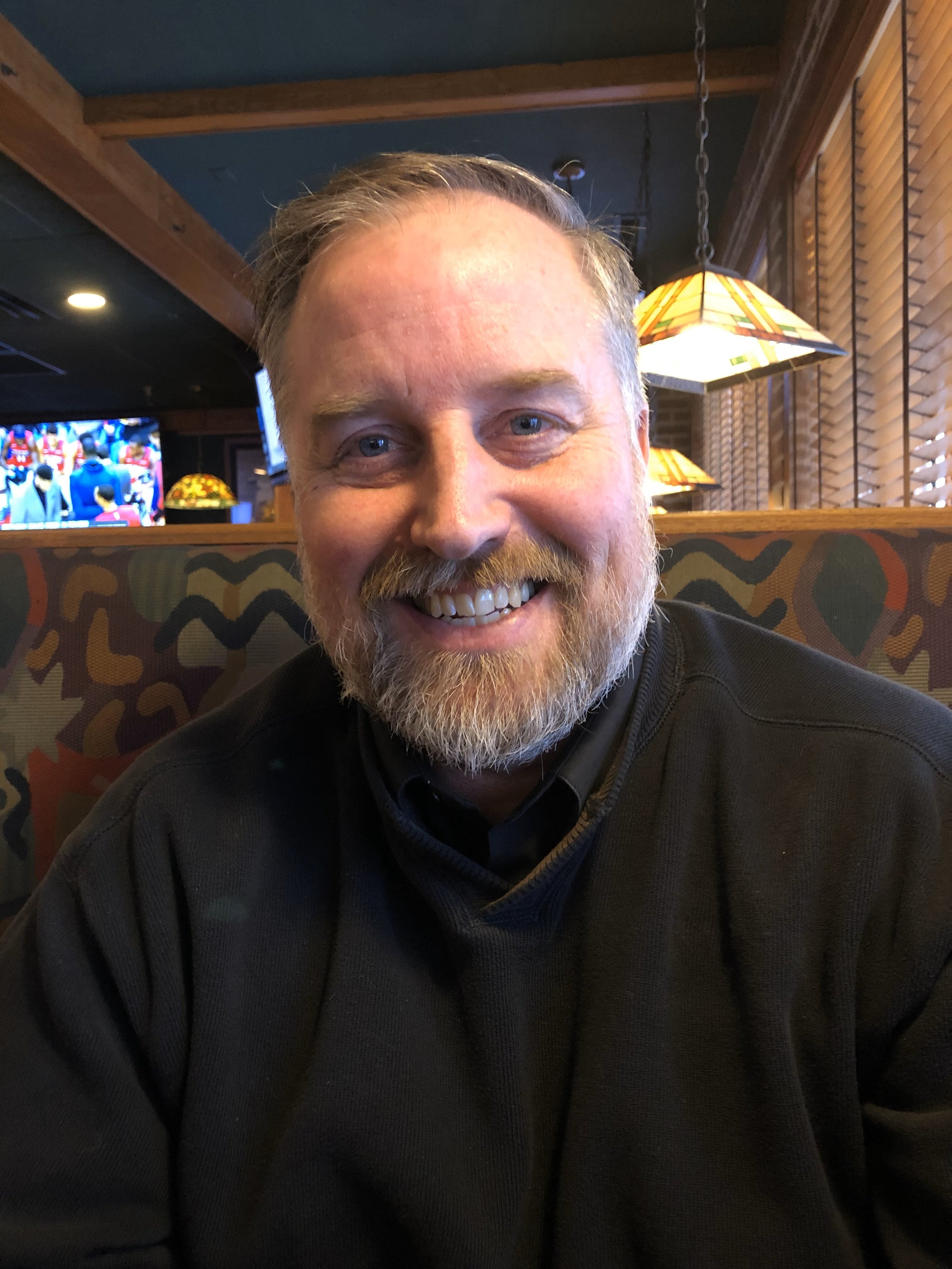 a middle-aged man with a beard smiling at the camera.