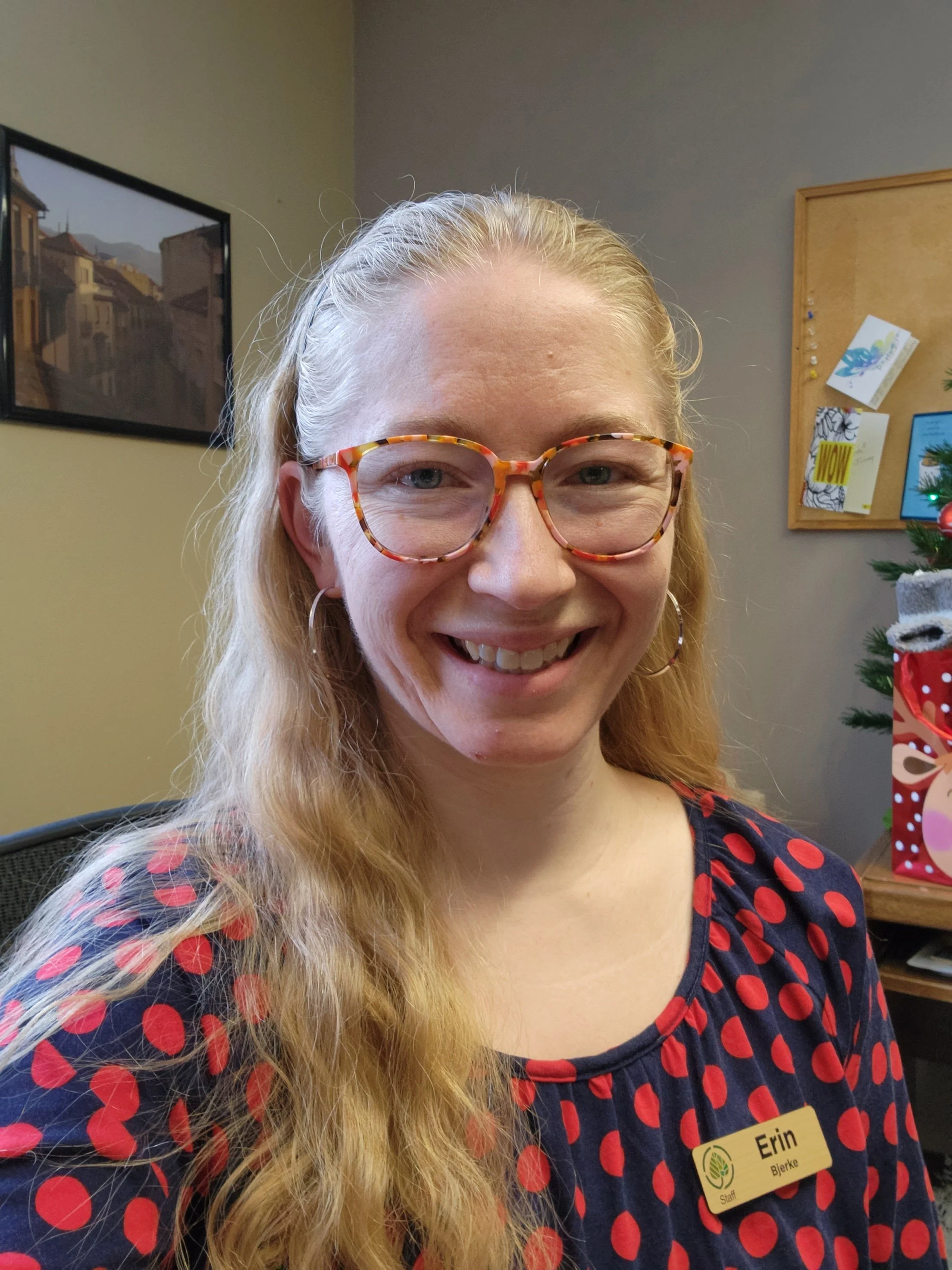 a young woman with long blonde hair and glasses smiling at the camera