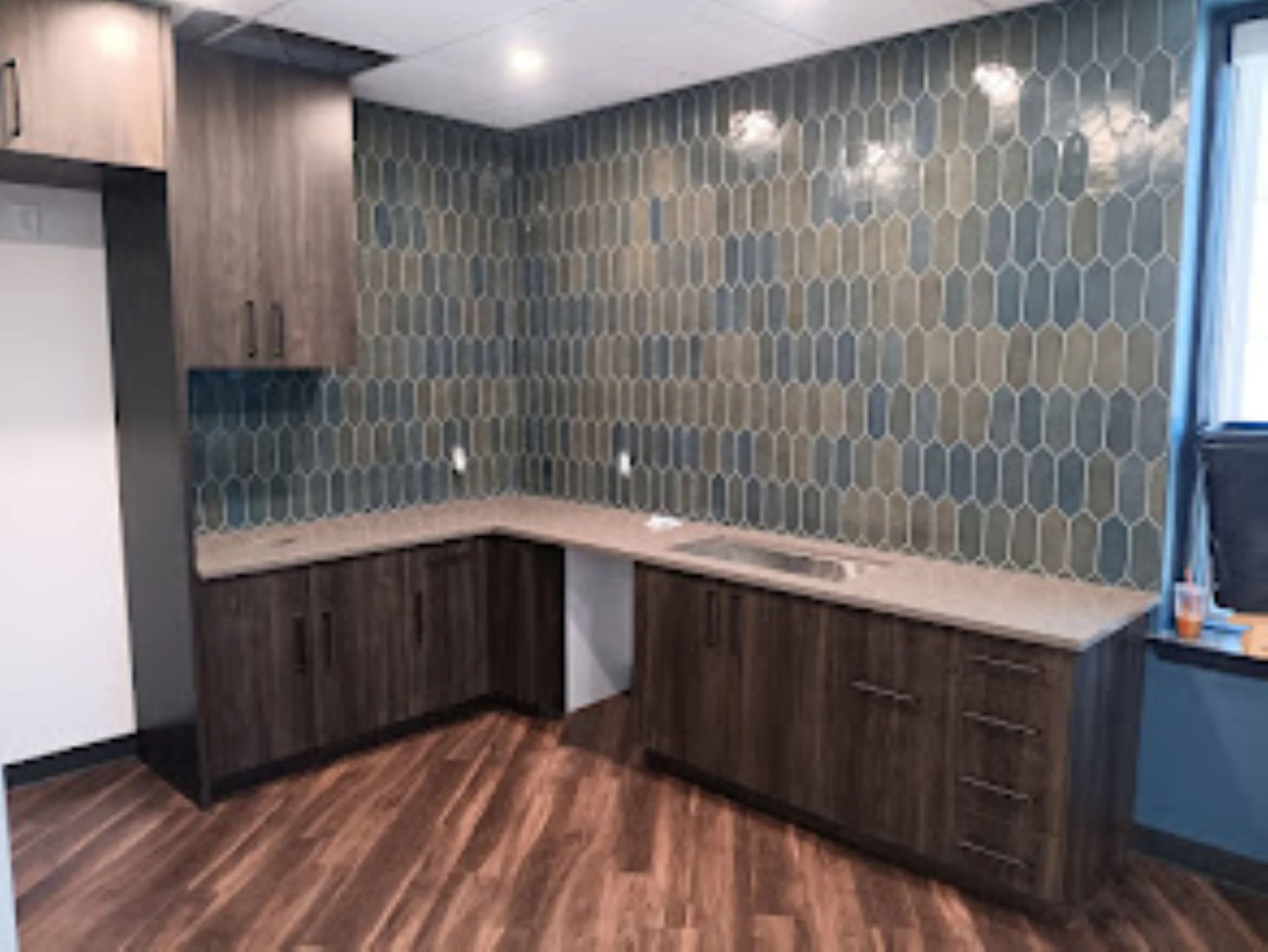 Kitchen with hexagonal dark gray wall tiles and wood flooring, creating a modern geometric backsplash design. Perfect for kitchen remodels, backsplash tile installation, and contemporary interior design.