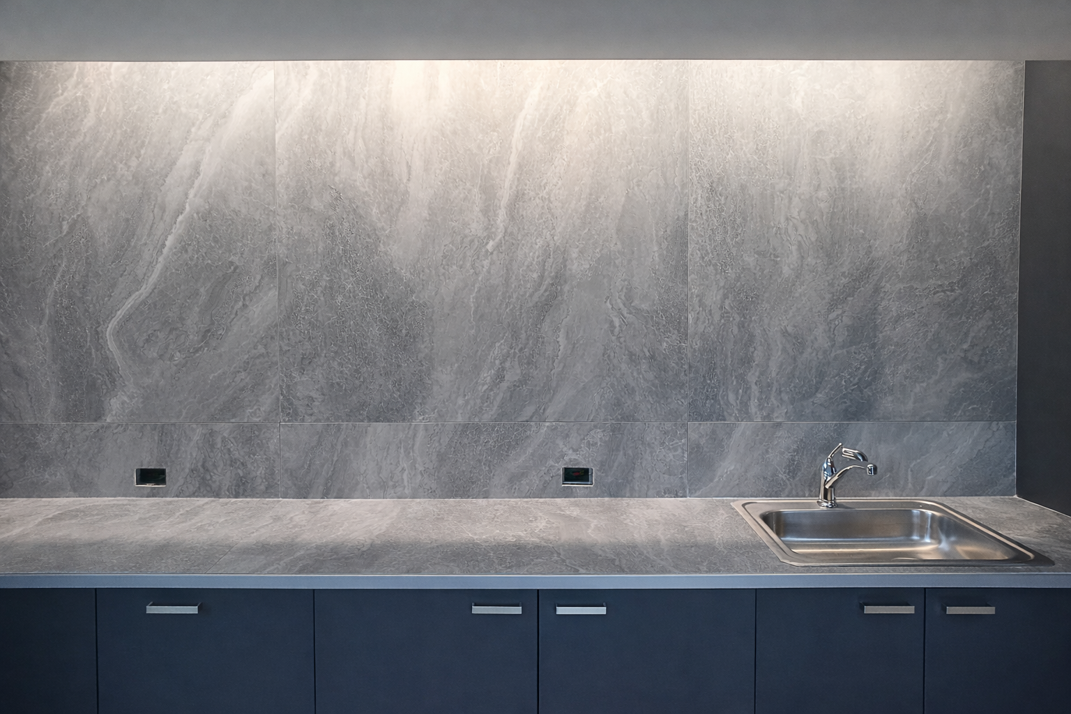 Modern kitchen with gray marble backsplash, gray countertop, a stainless steel sink, and blue cabinetry.