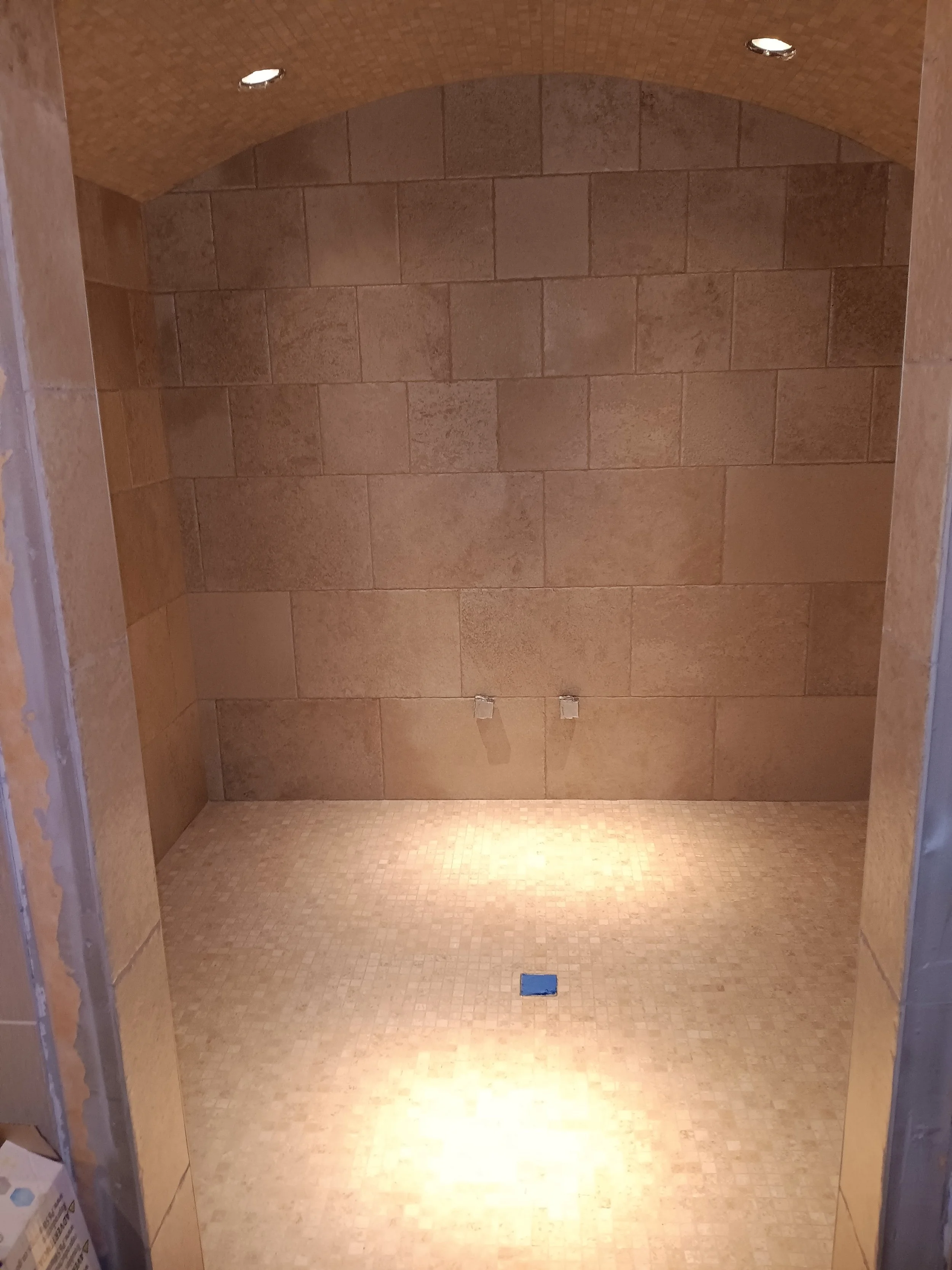 Empty shower stall with tiled walls and floor, no fixtures or accessories installed yet.