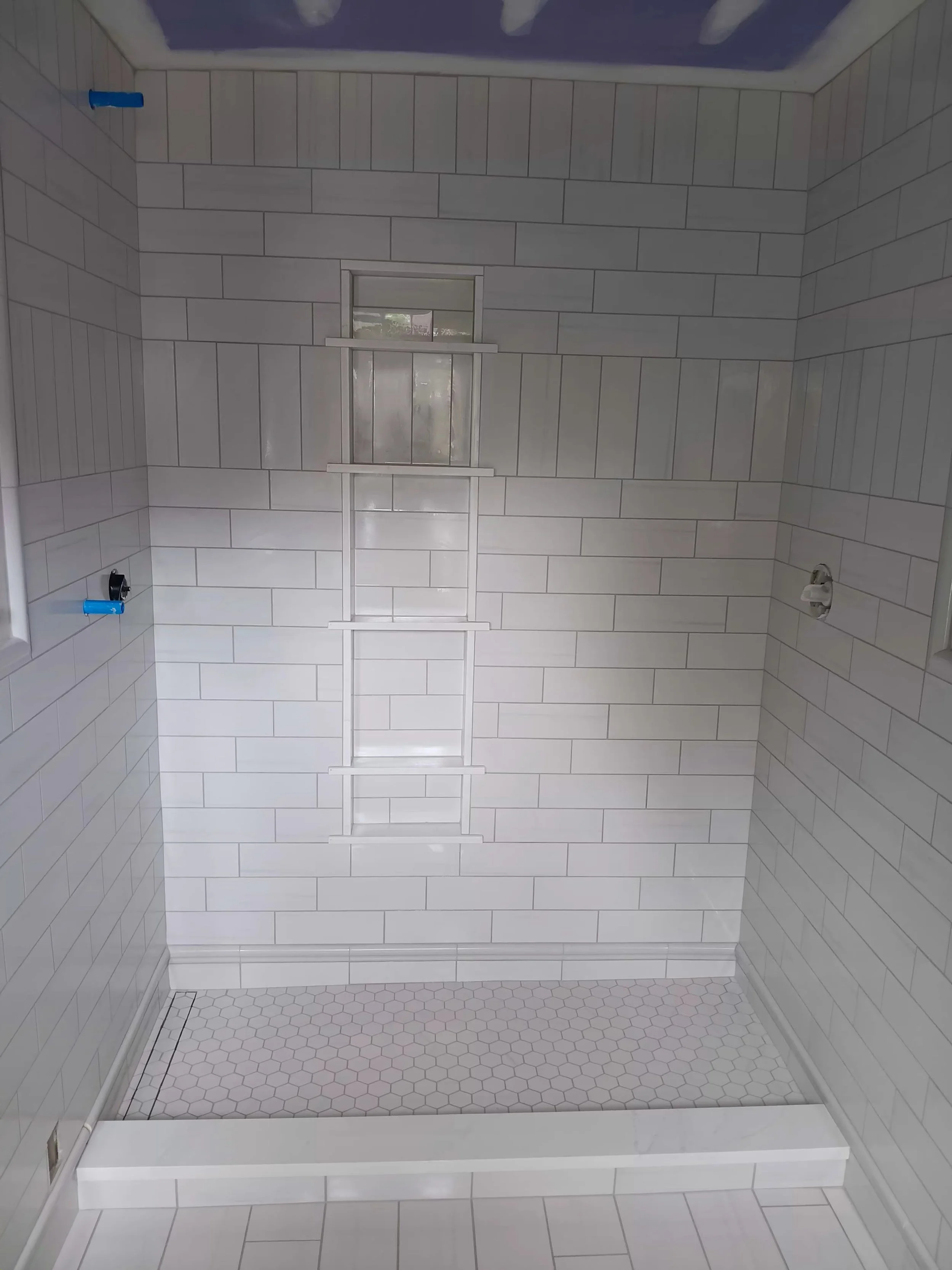  walk-in shower with white subway tile walls, hexagonal floor tiles, 