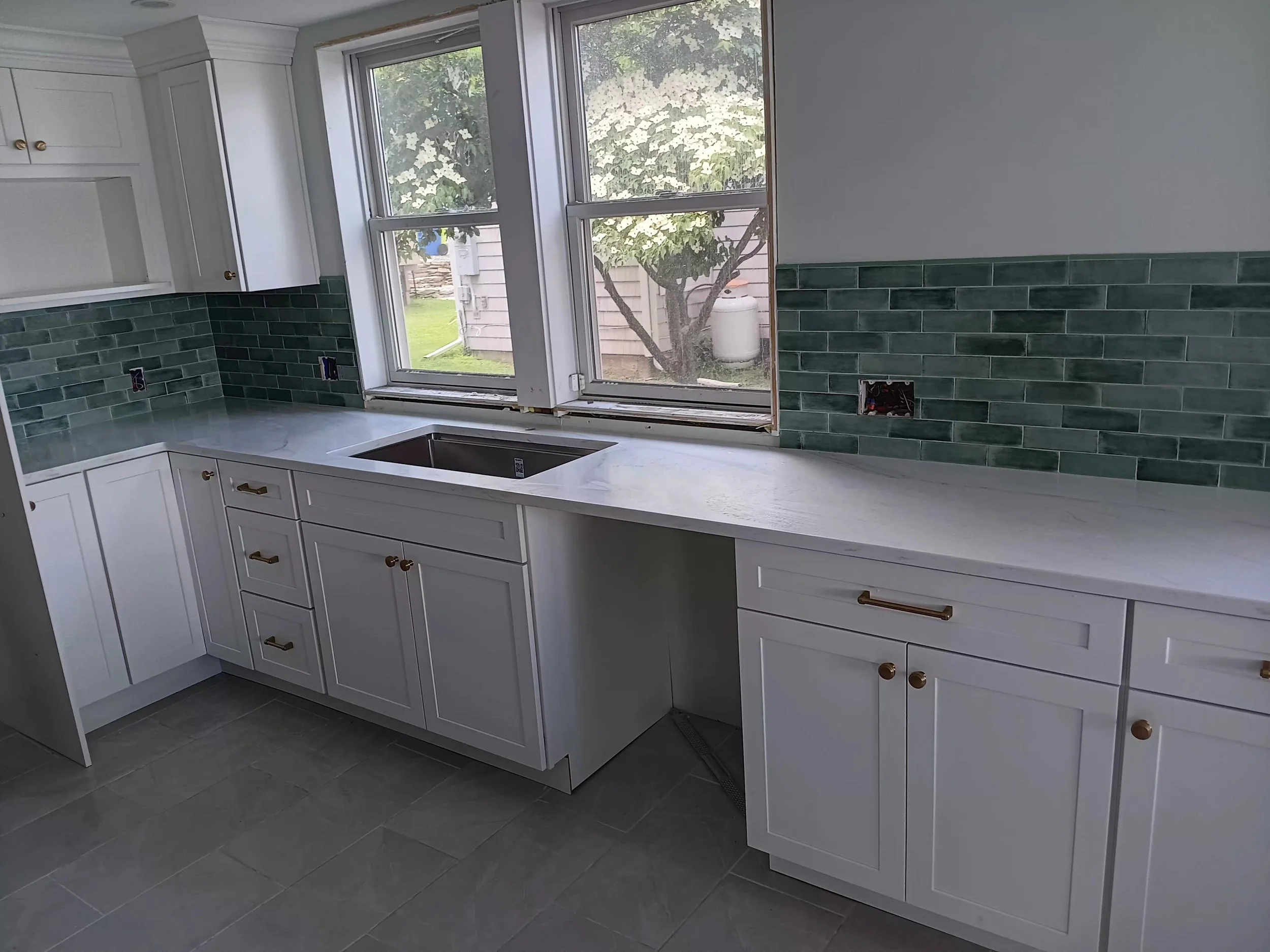 Kitchen with white cabinets, a marble countertop, green subway tile backsplash