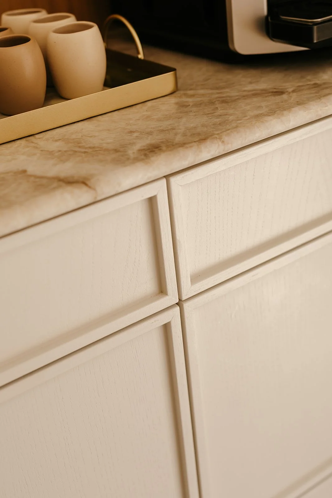 Détail des façades d'une cuisine blanche laissant apparaître le veinage du bois et l'alignement précis des tiroirs