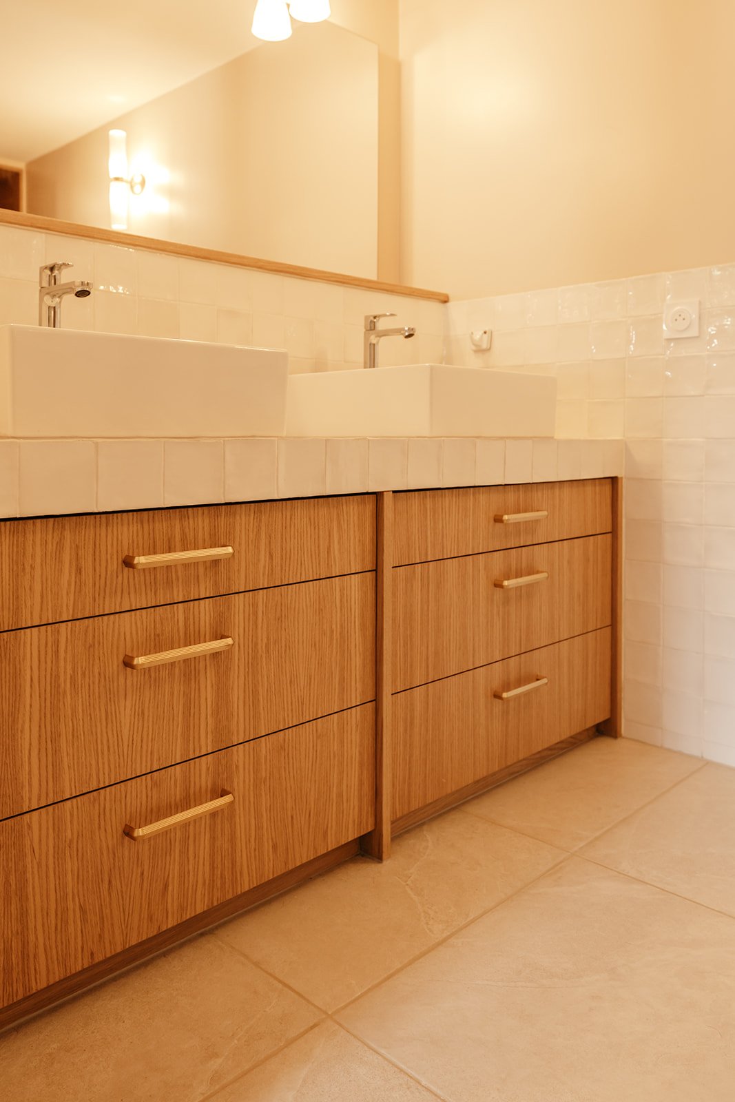 Meuble sous vasque en bois avec poignées en laiton dans une salle de bain contemporaine
