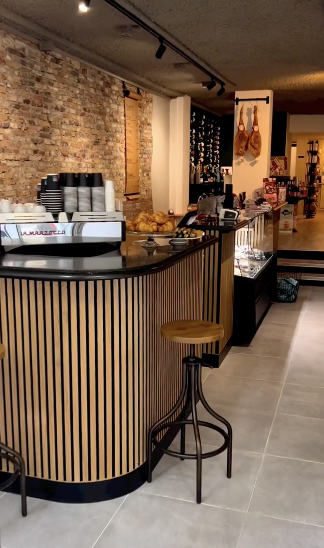 Agencement professionnel sur mesure avec un comptoir de magasin en bois, tasseaux verticaux et plateau en marbre conçu par Atelier Set