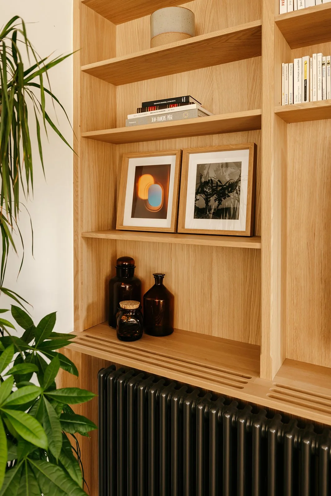 Bibliothèque en chêne avec étagères ouvertes et radiateur en fonte intégré à l'aménagement