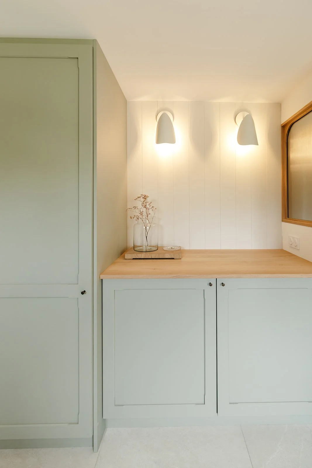 Meuble d'entrée peint en vert sauge avec rangements intégrés pour aspirateur, imprimante et objets du quotidien