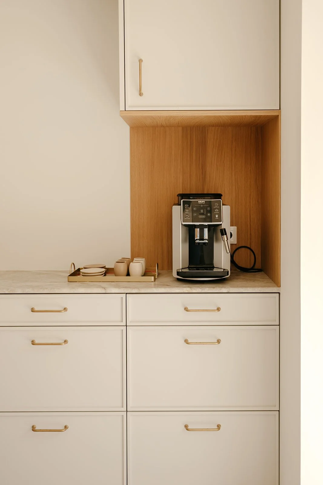 Détail d'une cuisine en bois peinte en blanc avec machine à café et aménagement intégré