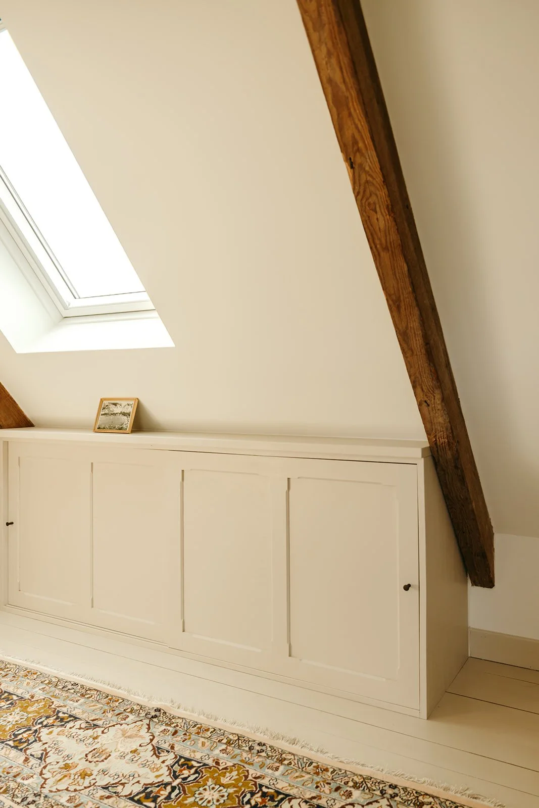 Aménagement sous pente avec meuble de rangement en bois sur mesure et portes coulissantes
