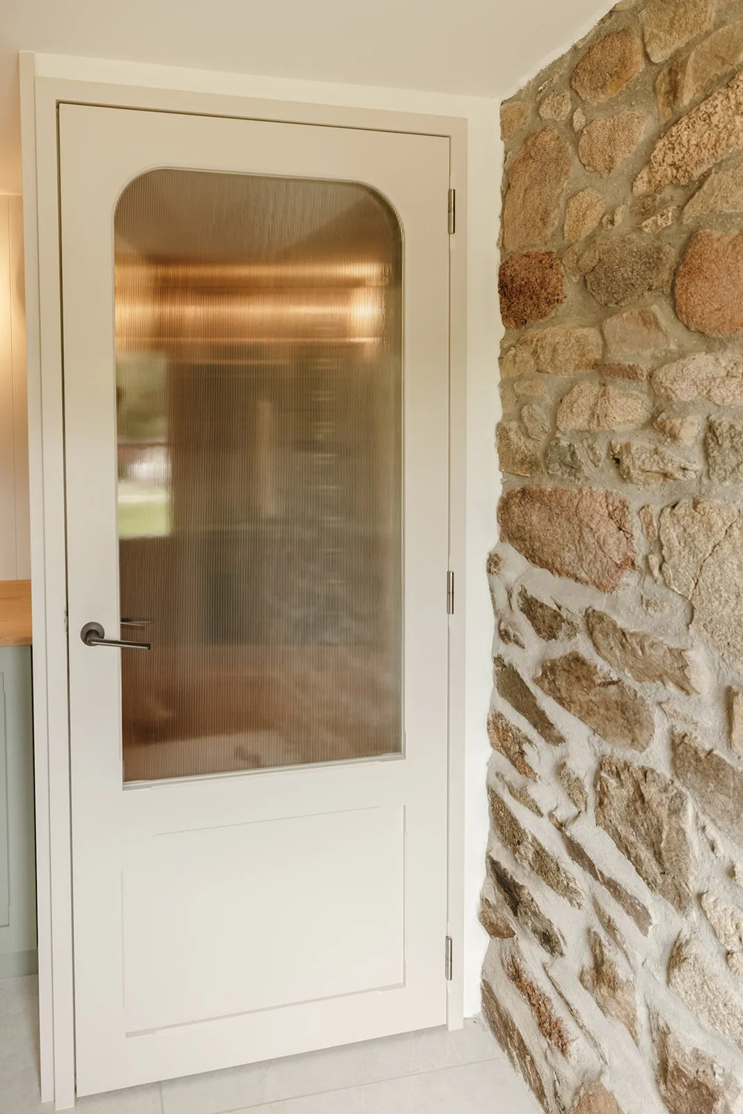Porte intérieure en chêne avec vitrage strié intégrée dans un aménagement sur mesure