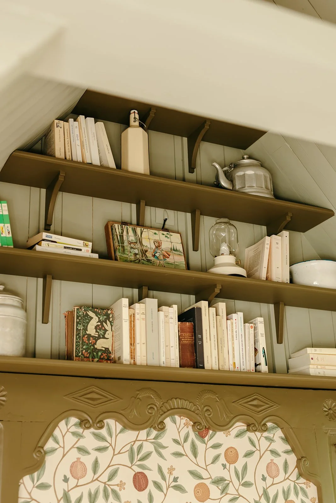 Détail d'une tête de lit en bois intégrée à une bibliothèque avec rangements dans une chambre à l'esprit campagne chic
